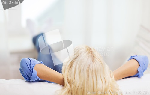 Image of young woman lying or sitting on sofa at home