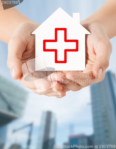 Image of hands holding paper house with red cross