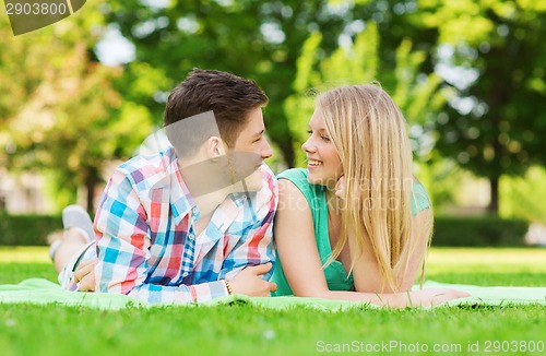 Image of smiling couple lying on blanket in park