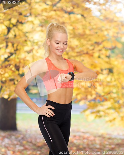 Image of smiling woman with heart rate monitor on hand