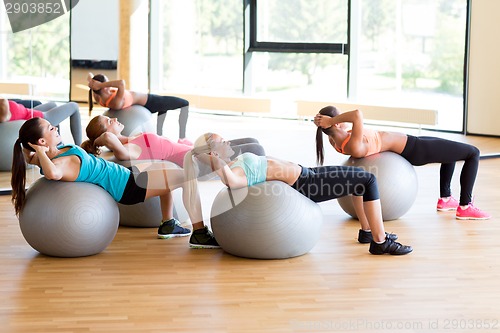 Image of group of smiling women with exercise balls in gym