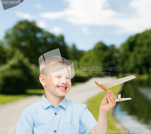 Image of smiling little boy holding a wooden airplane model