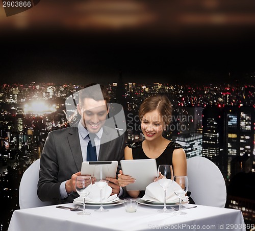 Image of couple with menus on tablet pc at restaurant