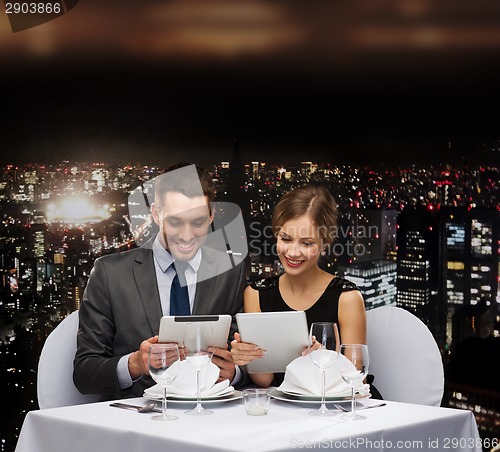Image of couple with menus on tablet pc at restaurant