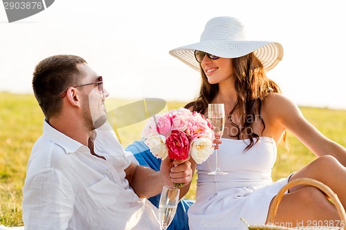 Image of smiling couple drinking champagne on picnic