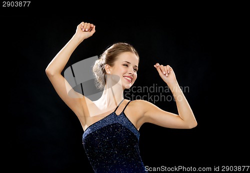 Image of smiling woman dancing with raised hands