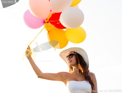 Image of smiling young woman in sunglasses with balloons