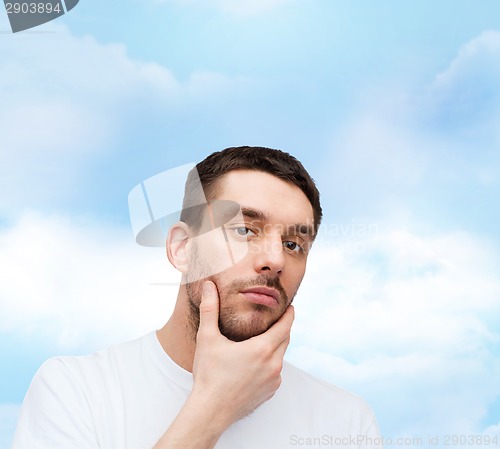 Image of beautiful calm man touching his face