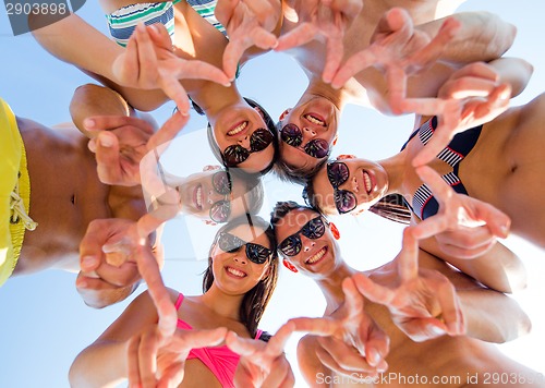 Image of smiling friends in circle on summer beach