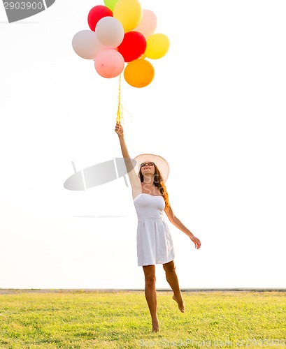 Image of smiling young woman in sunglasses with balloons