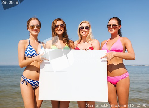 Image of group of smiling women with blank board on beach