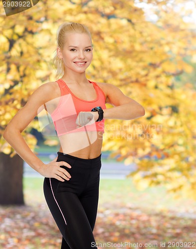 Image of smiling woman with heart rate monitor on hand