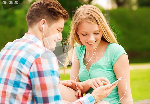 Image of smiling couple with smartphone and earphones