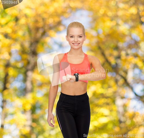 Image of smiling woman with heart rate monitor on hand