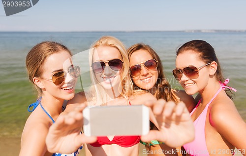 Image of group of smiling women making selfie on beach