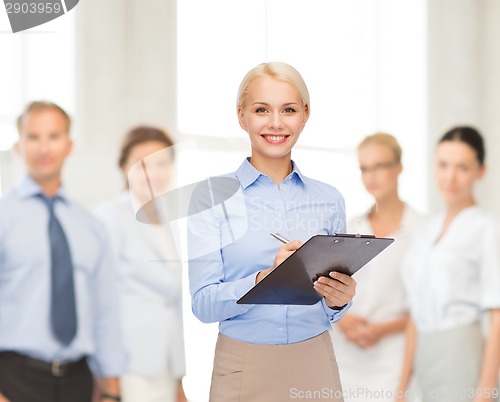 Image of smiling businesswoman with clipboard and pen