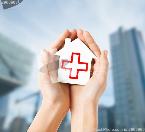 Image of hands holding paper house with red cross