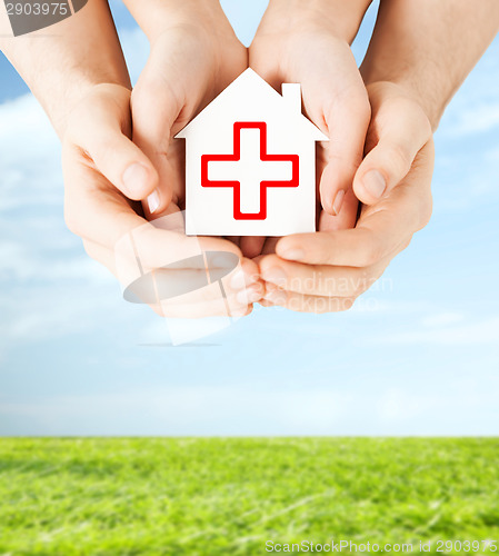 Image of hands holding paper house with red cross