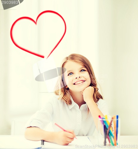 Image of smiling little student girl drawing at school