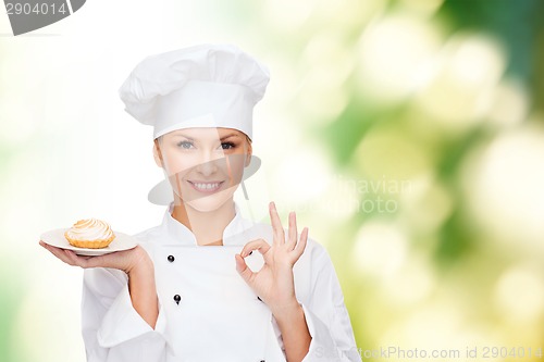 Image of smiling female chef with cake on plate