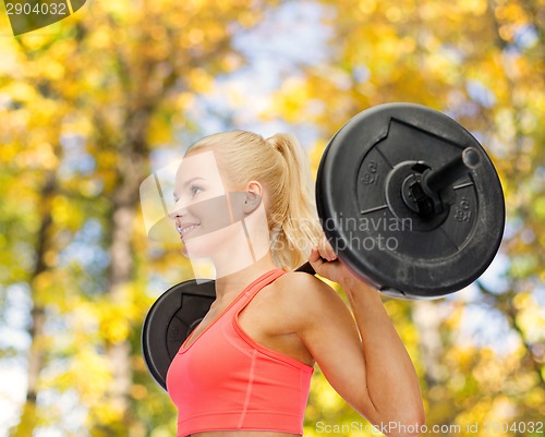 Image of smiling sporty woman exercising with barbell