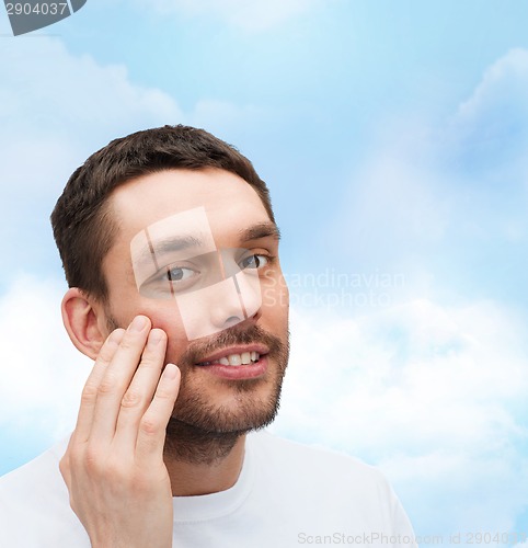 Image of beautiful smiling man touching his face