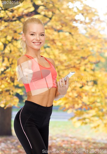 Image of smiling sporty woman with smartphone