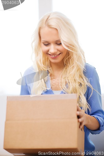 Image of smiling woman opening cardboard box at home