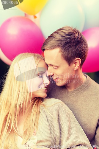 Image of couple with colorful balloons kissing in the park