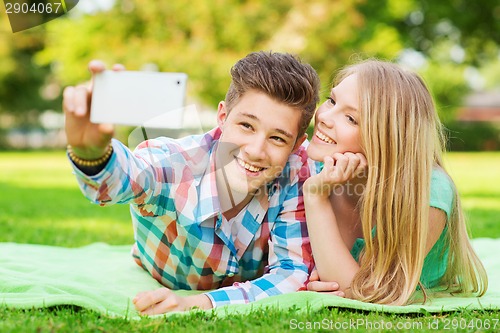 Image of smiling couple making selfie in park