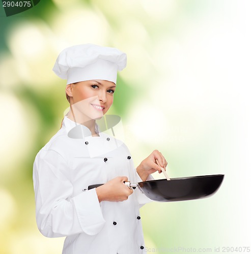 Image of smiling female chef with pan and spoon