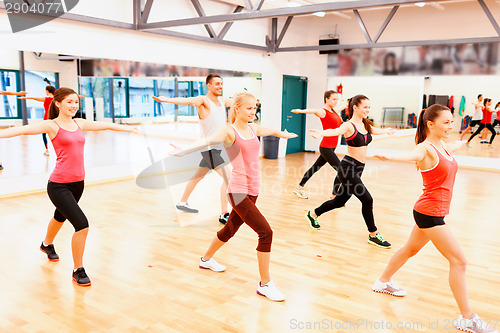 Image of group of smiling people exercising in the gym