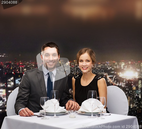 Image of smiling couple holding hands at restaurant