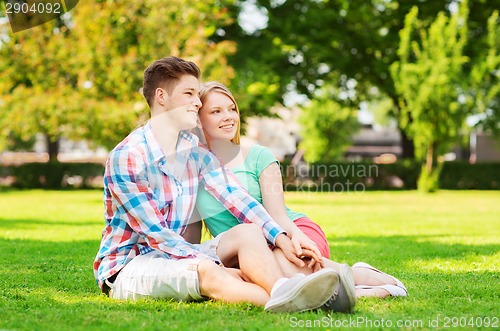 Image of smiling couple sitting on grass in park