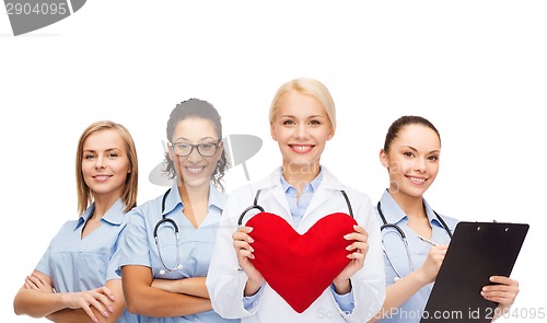 Image of smiling female doctor and nurses with red heart