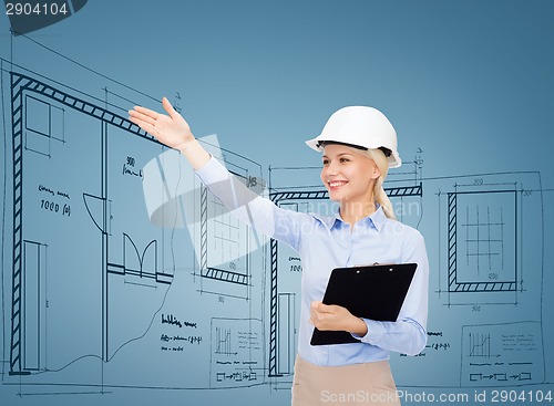 Image of smiling businesswoman in helmet with clipboard