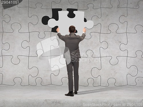 Image of businessman in suit setting piece of puzzle