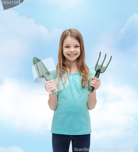 Image of smiling little girl with rake and scoop