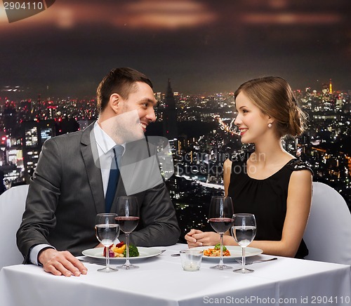 Image of smiling couple eating main course at restaurant