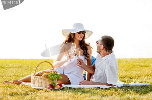 Image of smiling couple drinking champagne on picnic