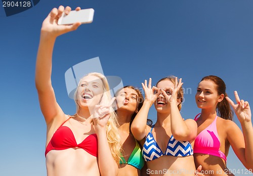 Image of group of smiling women making selfie on beach