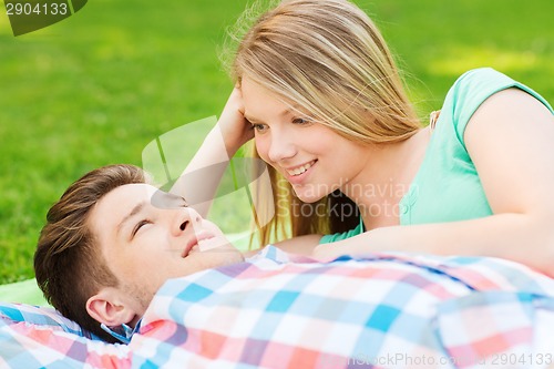 Image of smiling couple lying on blanket in park