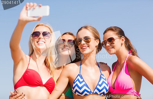 Image of group of smiling women making selfie on beach