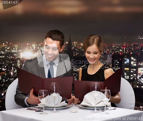 Image of smiling couple with menus at restaurant