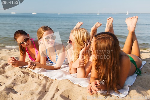 Image of group of smiling women in sunglasses on beach