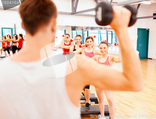 Image of group of smiling female with dumbbells and step