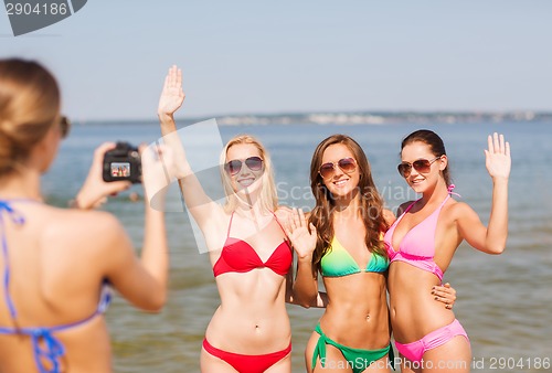 Image of group of smiling women photographing on beach