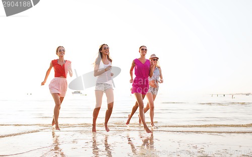 Image of group of smiling women running on beach
