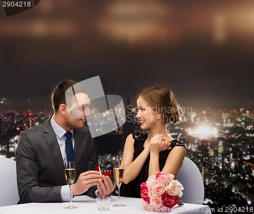 Image of man proposing to his girlfriend at restaurant