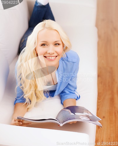 Image of woman lying on couch and reading magazine at home